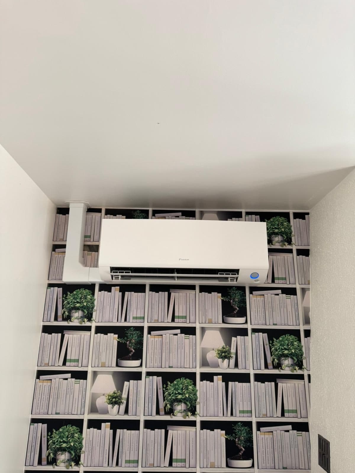 Unité murale de climatisation Daikin installée dans un bureau, goulotte verticale blanche
