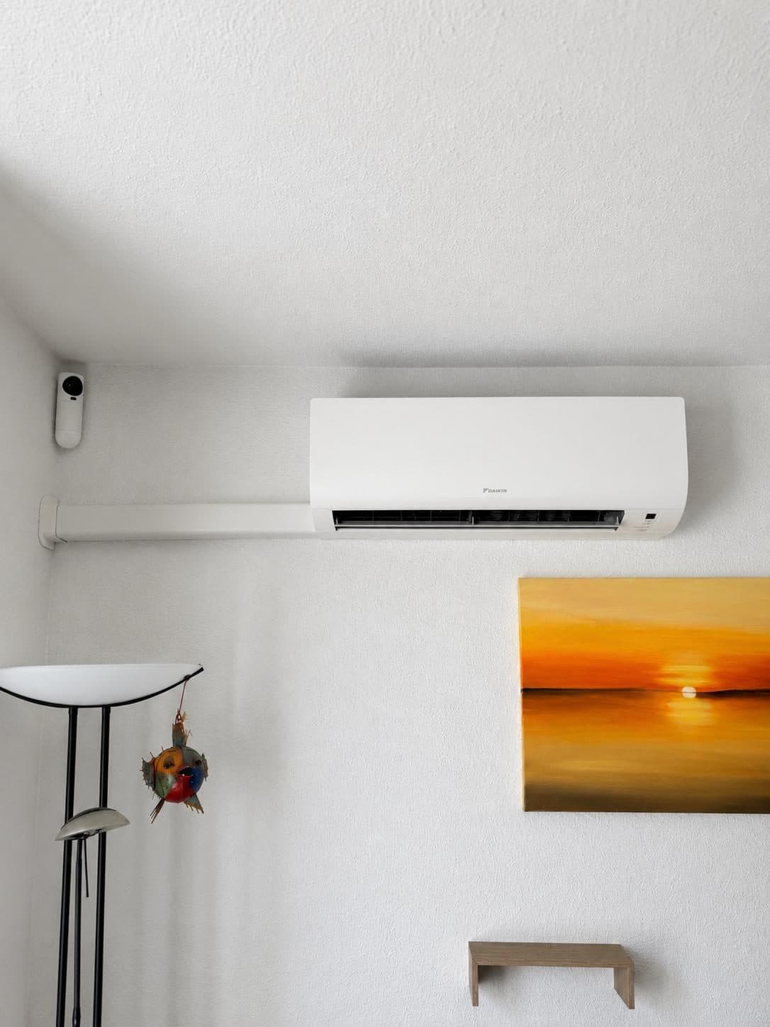 Unité murale de climatisation Daikin dans un salon, avec goulotte horizontale blanche
