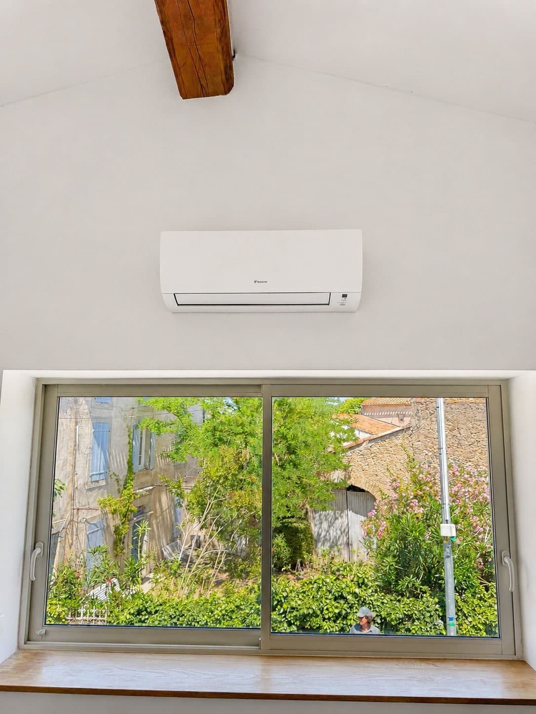 Unité murale de climatisation Daikin posée sous charpente dans une maison de village rénovée